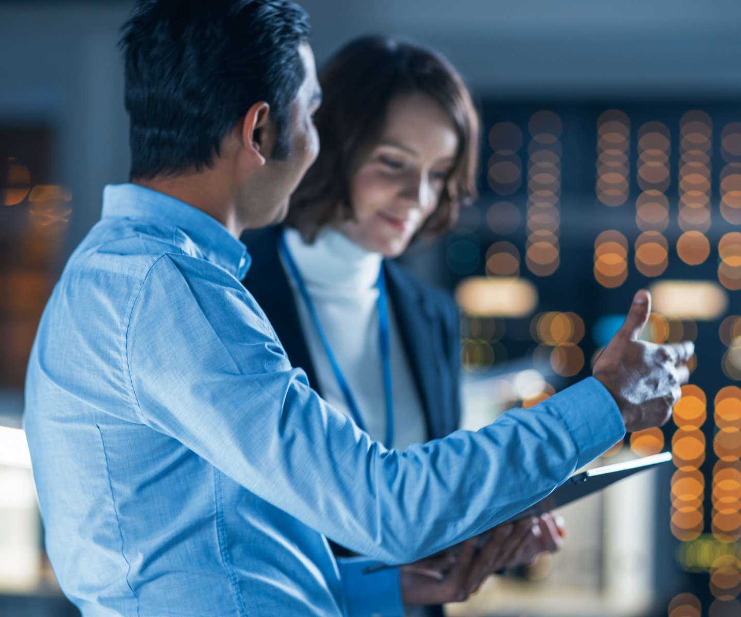 two people in suits looking at a tablet device whilst having a discussion